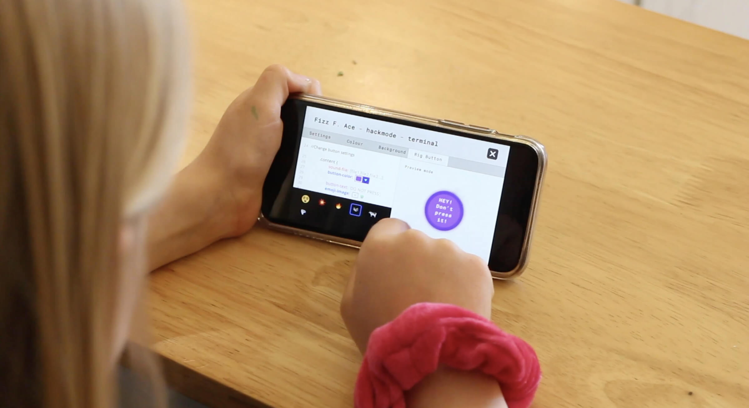 A child holding a phone showing the Hackmode terminal screen, with a 'don't press it' warning button