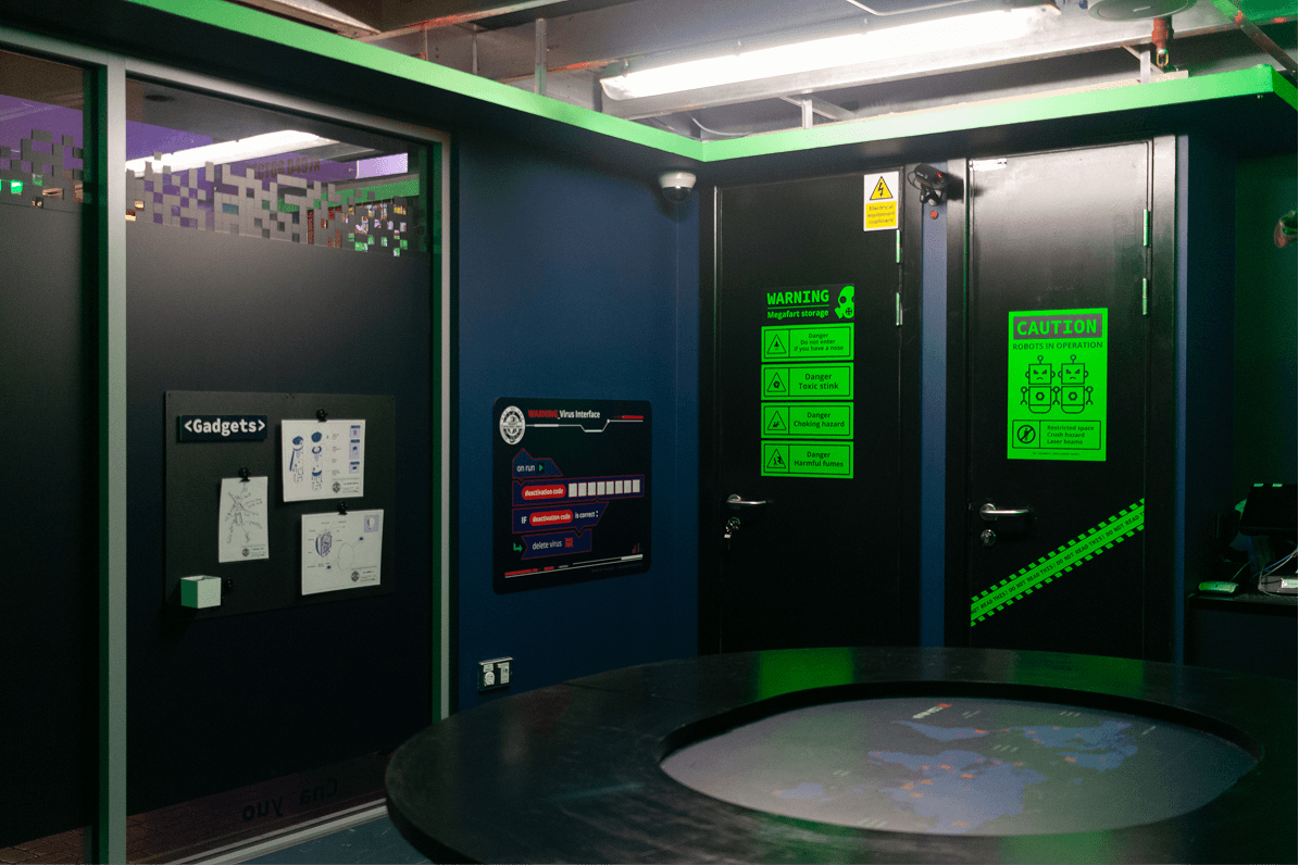 Interior view of the room showing the interactive round table, gadgets board and warning doors