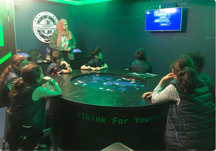 A group of children sat around the interactive round table during a session, led by a member of staff