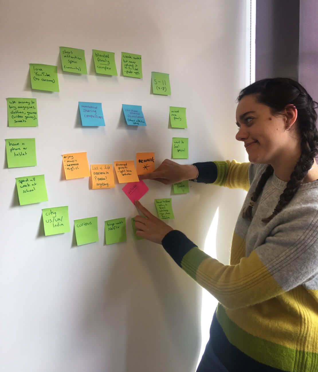 Lucrecia pointing at a wall of sticky notes during a research and affinity-mapping session